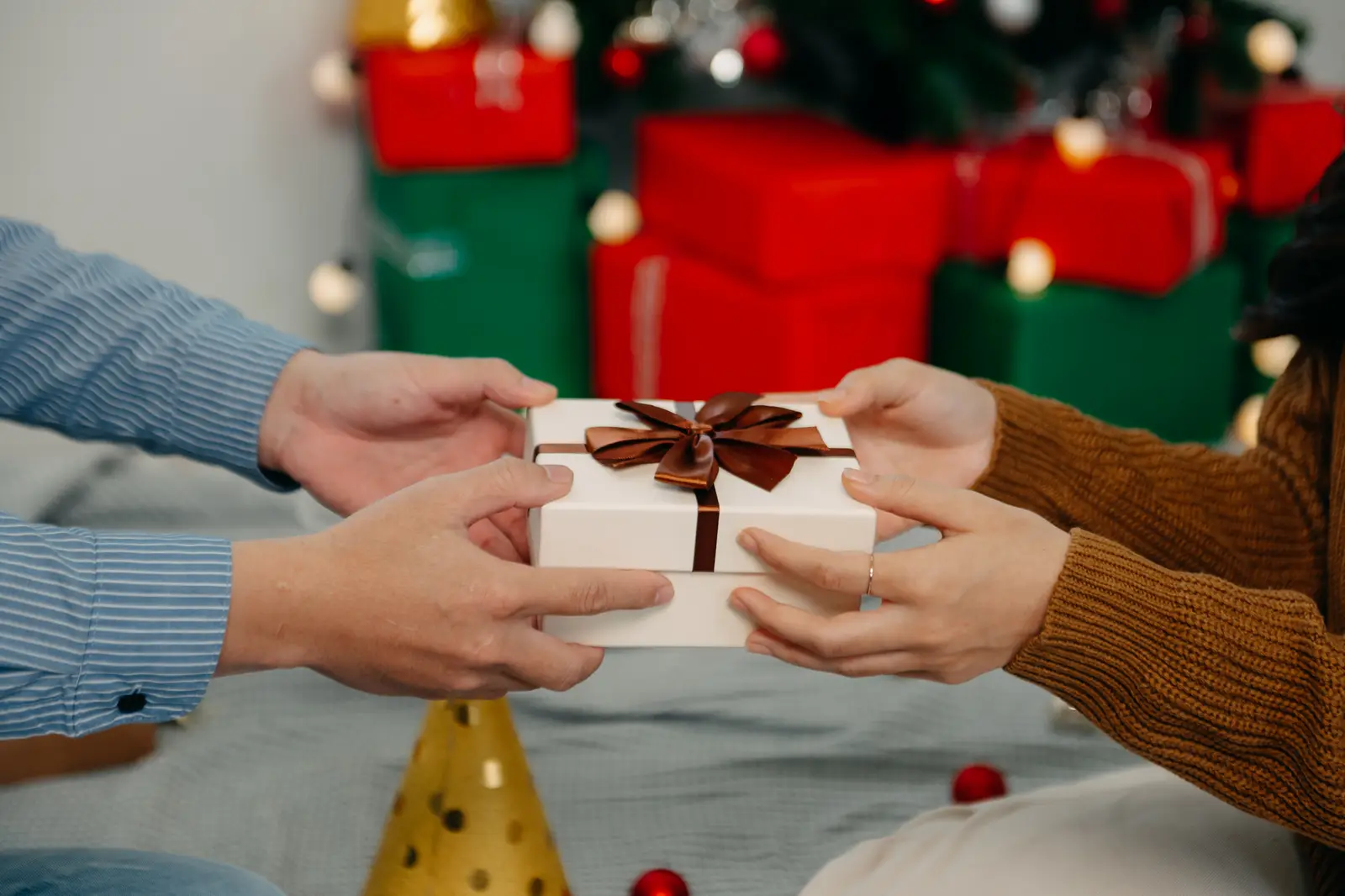 Festive corporate gift exchanged in front of a decorated tree
